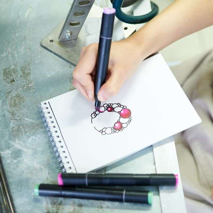 A person drawing a jewelry and applying colors on it